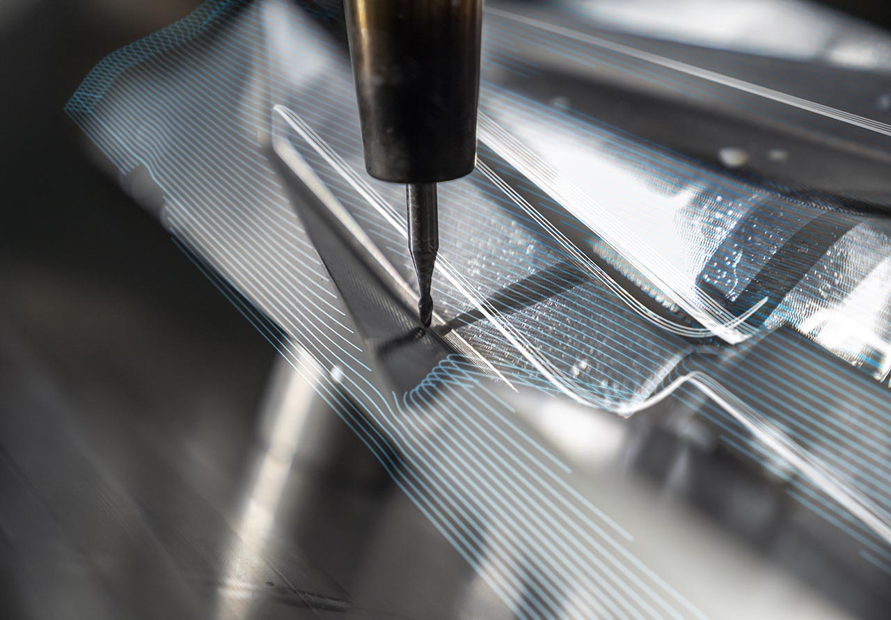 Autodesk customer, Hermle, uses PowerMill to create its machines. Here they are milling the PowerMill hero object from metal. A wireframe overlay of the object's data set has been added to this image.